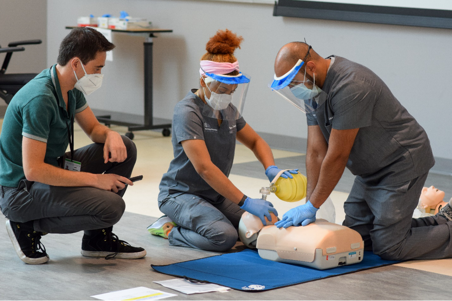 Three students perform cpr on manikin