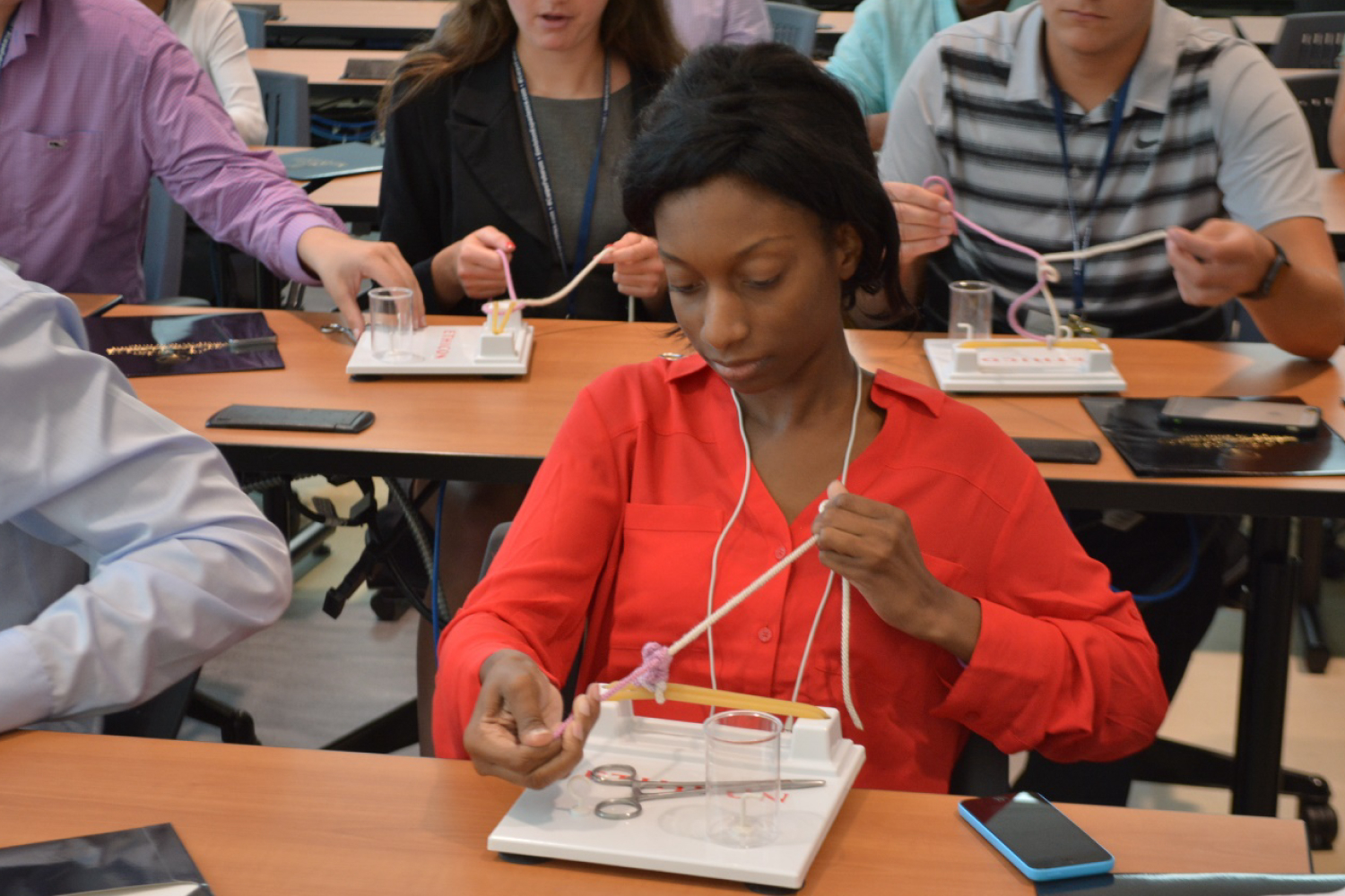 Students sitting at desks and learning to tie medical knots