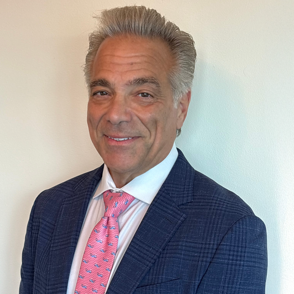 man with short gray hair wearing blue suit jacket and pink tie