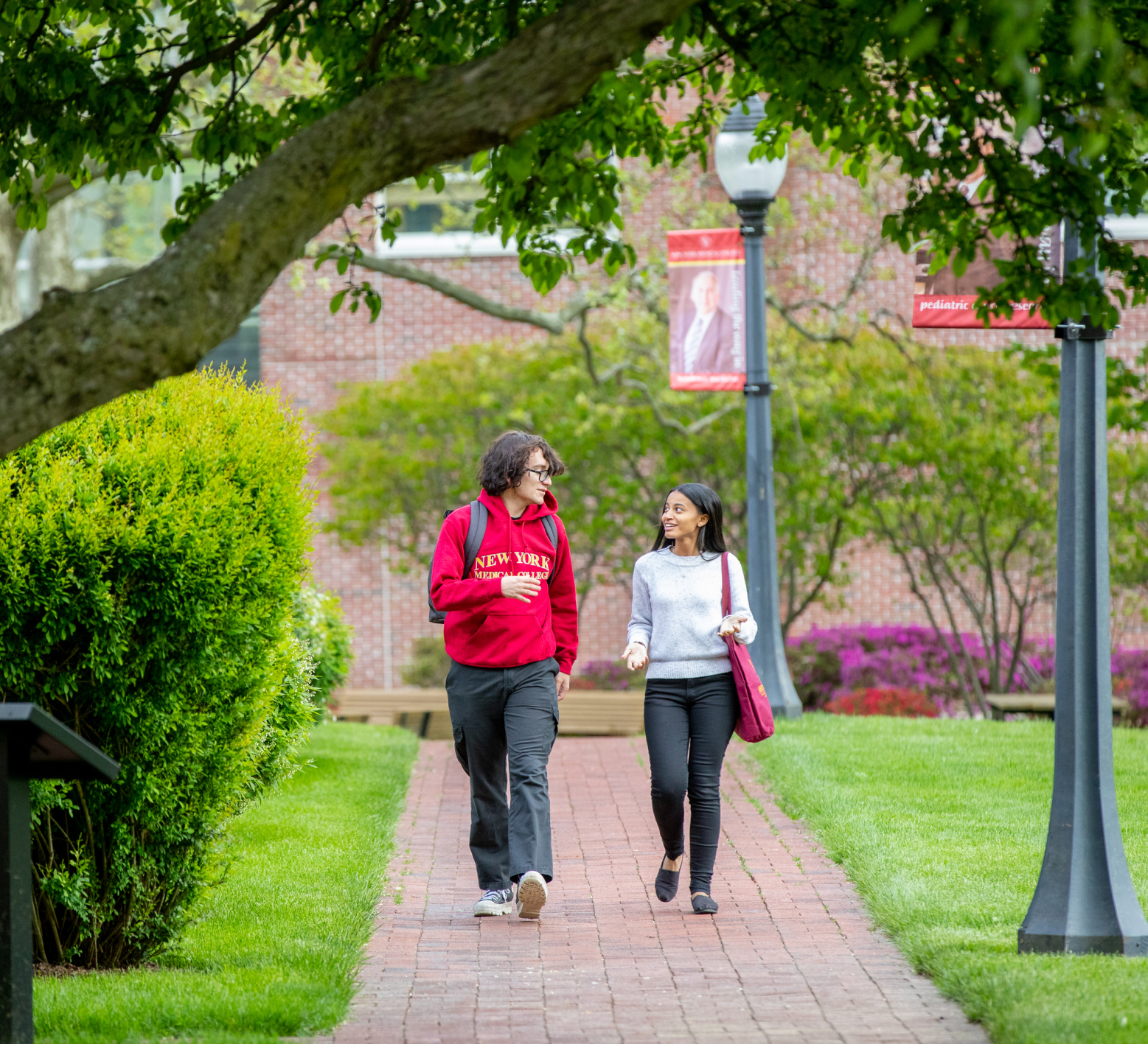 Two students walking on together on campus surrounded by greenery