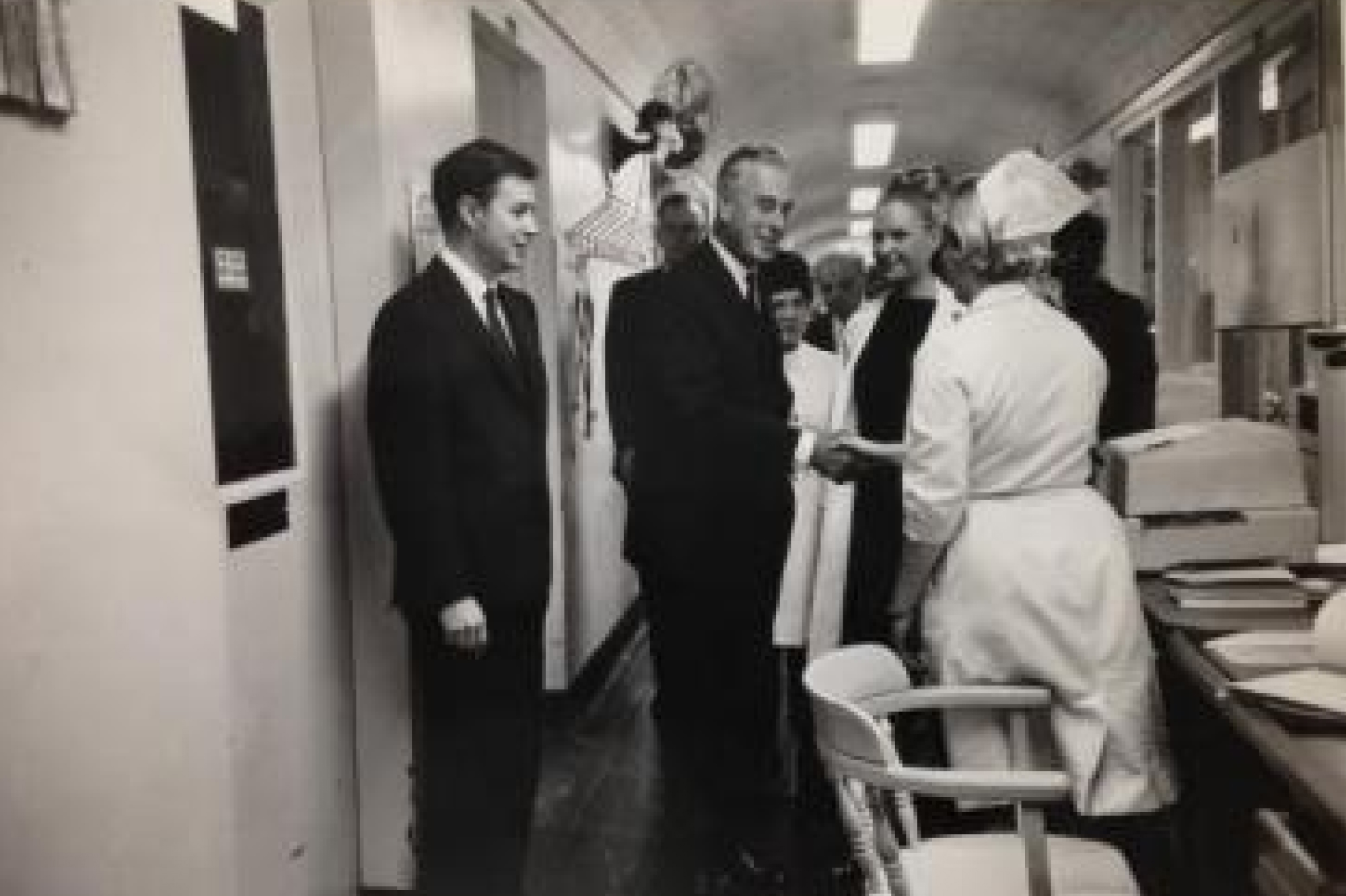 Prince Philip smiling while chatting with the board of trustees chair and the chair of pediatrics in hallway of flower-fifth avenue hospital