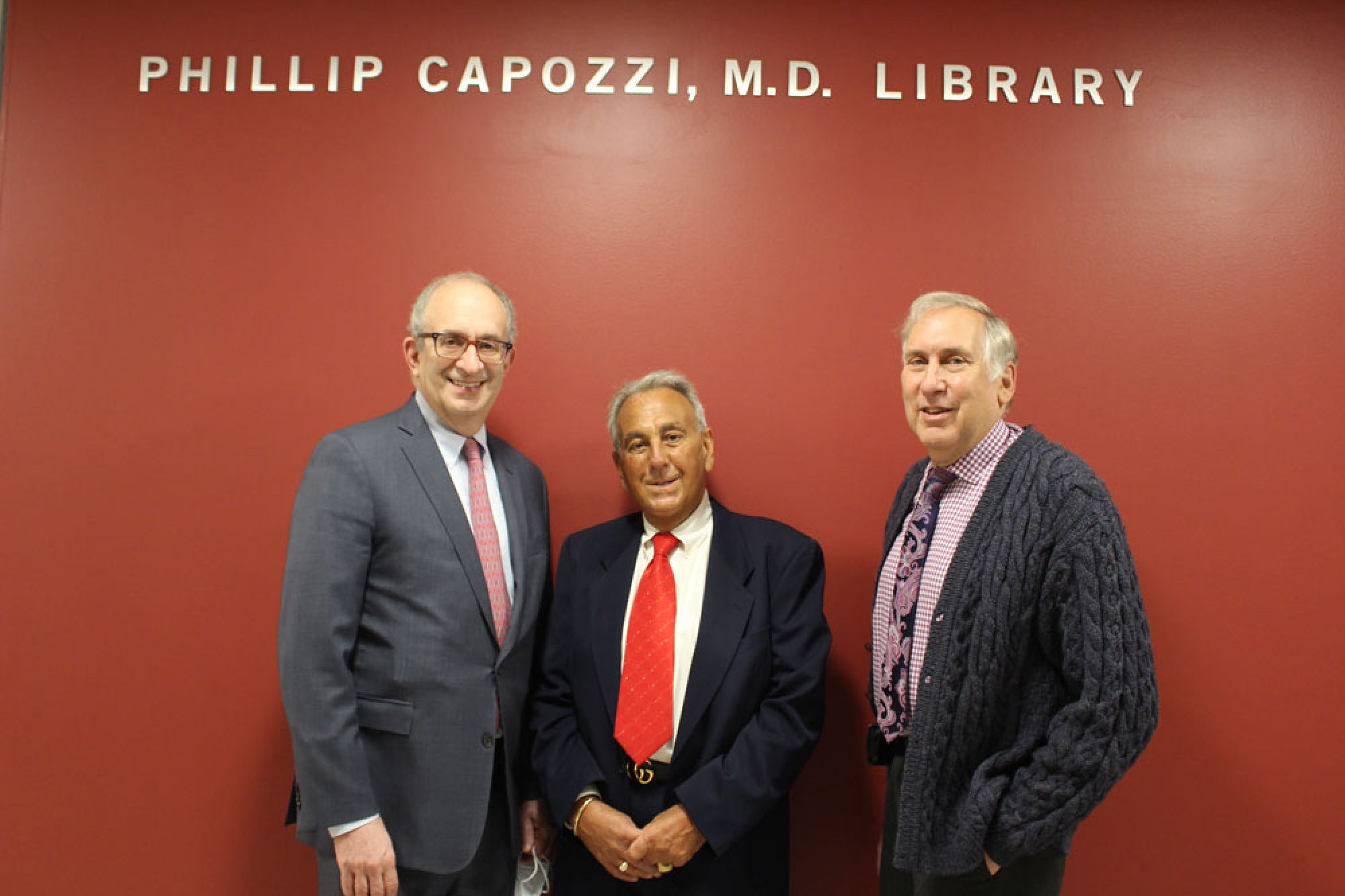 Dr. Kadish, Philip D. Capozzi, and Edward C. Halperin smiling under the library's sign