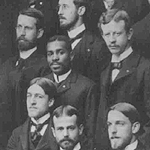 Black and white photograph of Alonzo Potter Burgess Holley. He is the only Black man in a group of white men. All are wearing identical suits, and look accomplished.