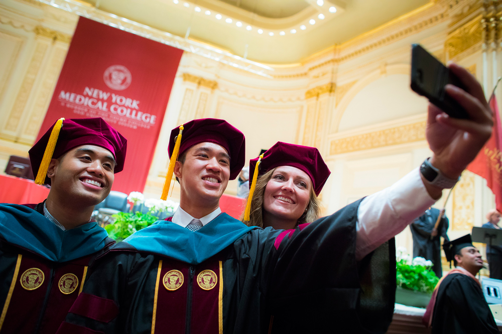 NYMC students taking a picture of themselves with the ceremony stage in the background