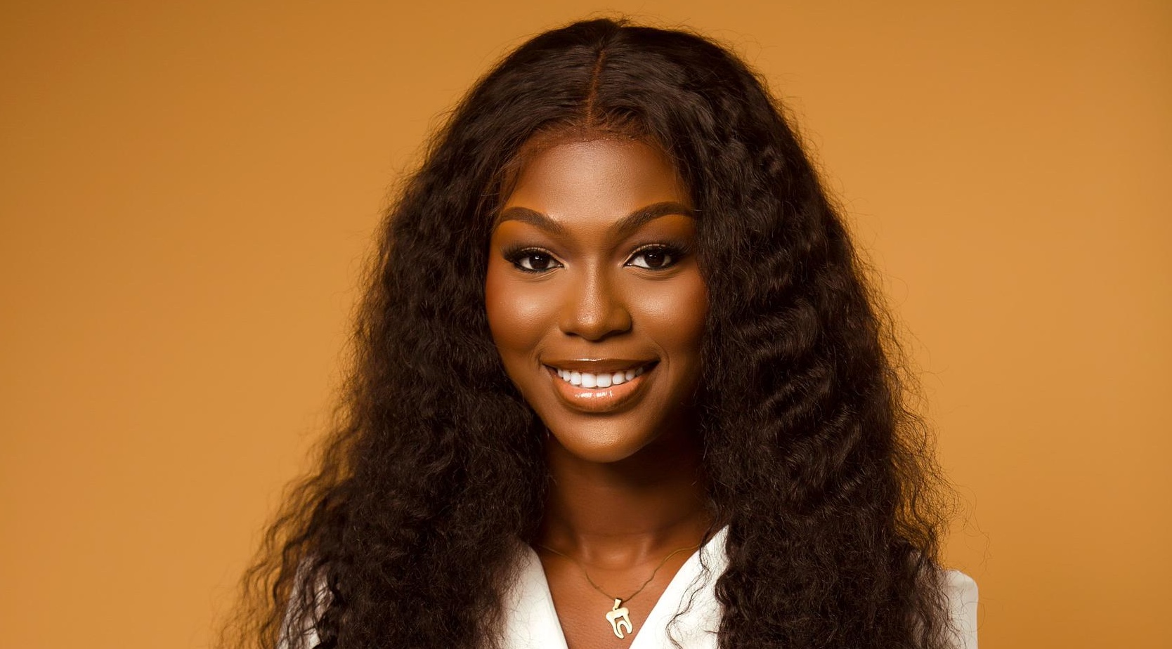 A woman smiling in front of an orange background