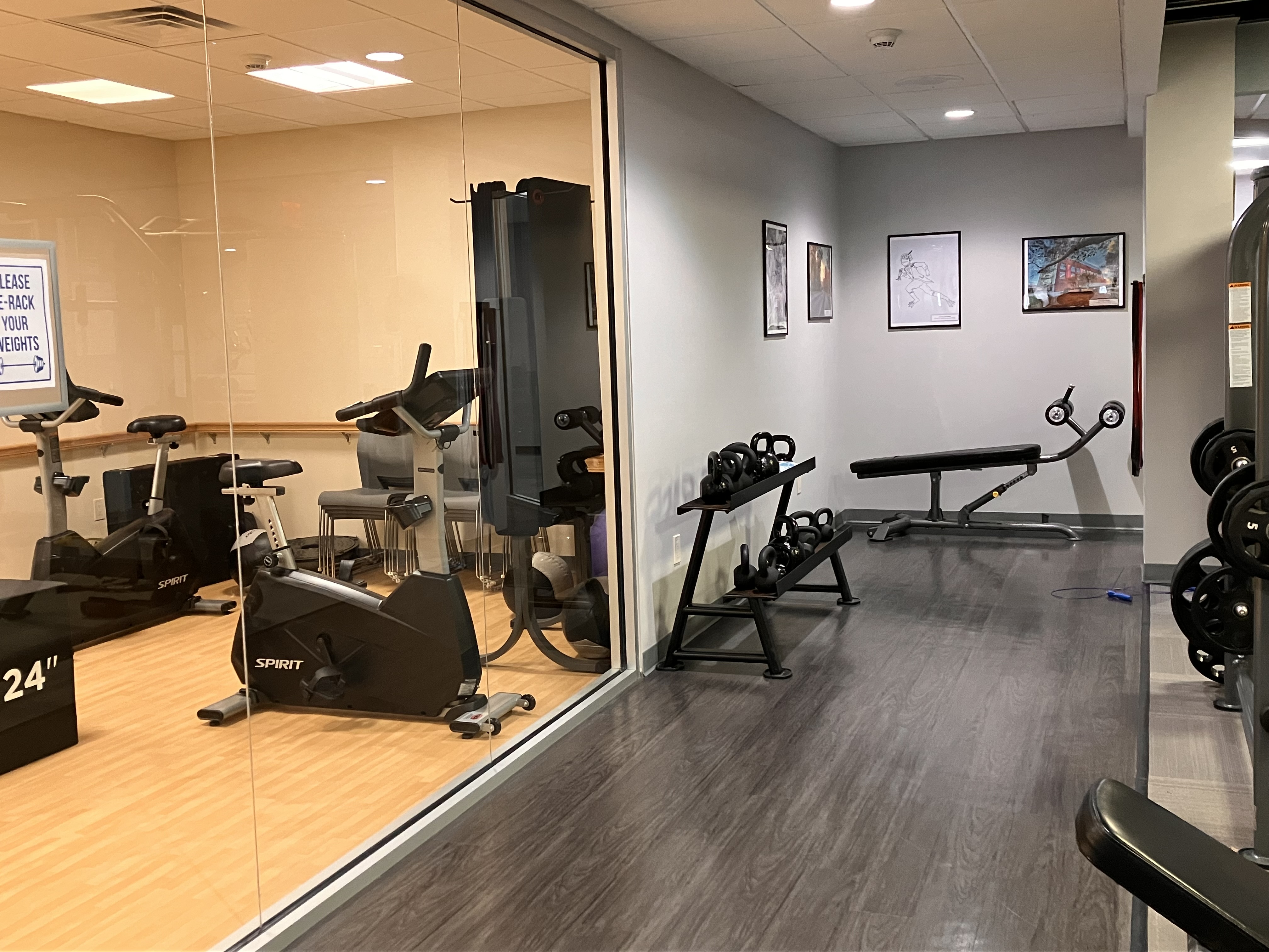 Fitness center with workout equipment and artwork on the walls.