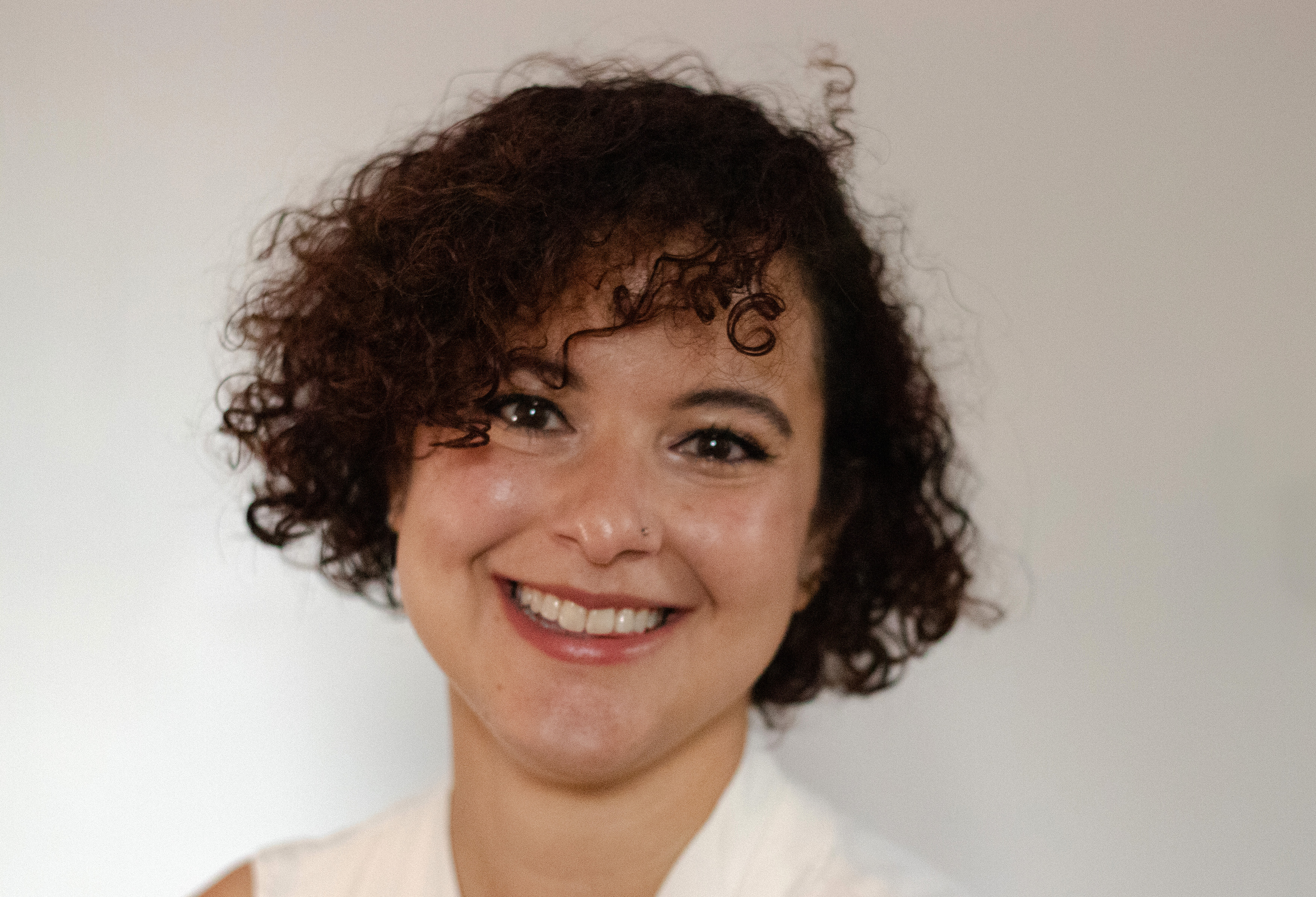 A woman with short curly hair smiling.