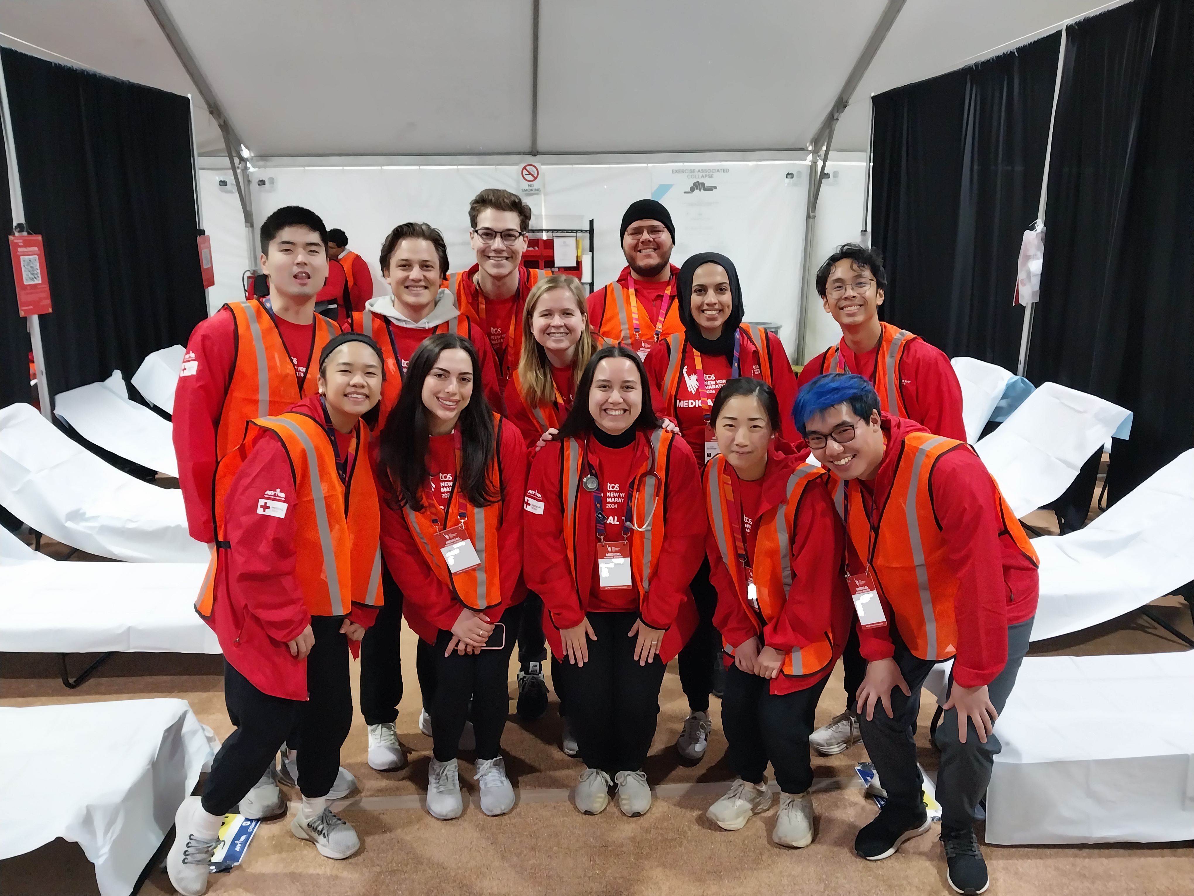 A group of medical students wearing volunteer jackets in a medical aid tent.