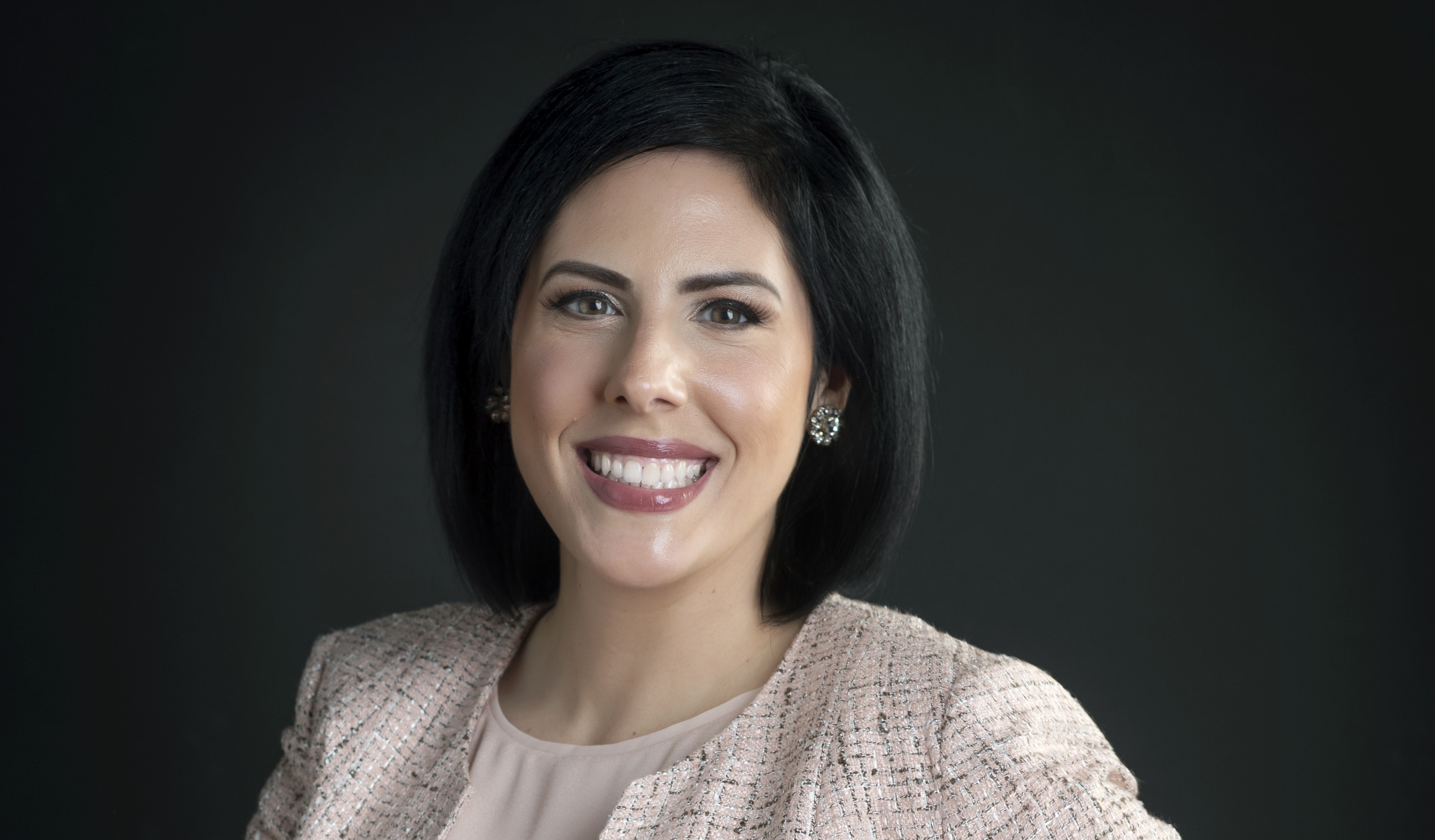 A woman smiling in front of a background