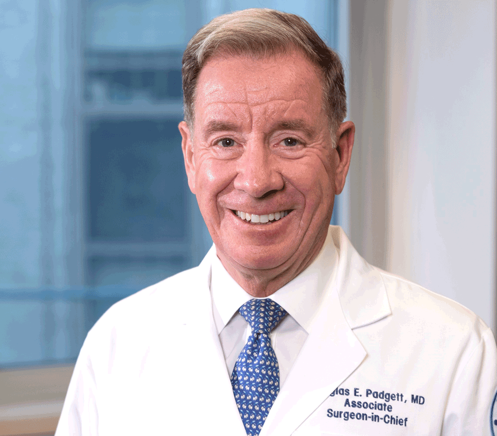 Douglas Padgett, M.D. ’82 wearing a white shirt, blue tie and lab coat