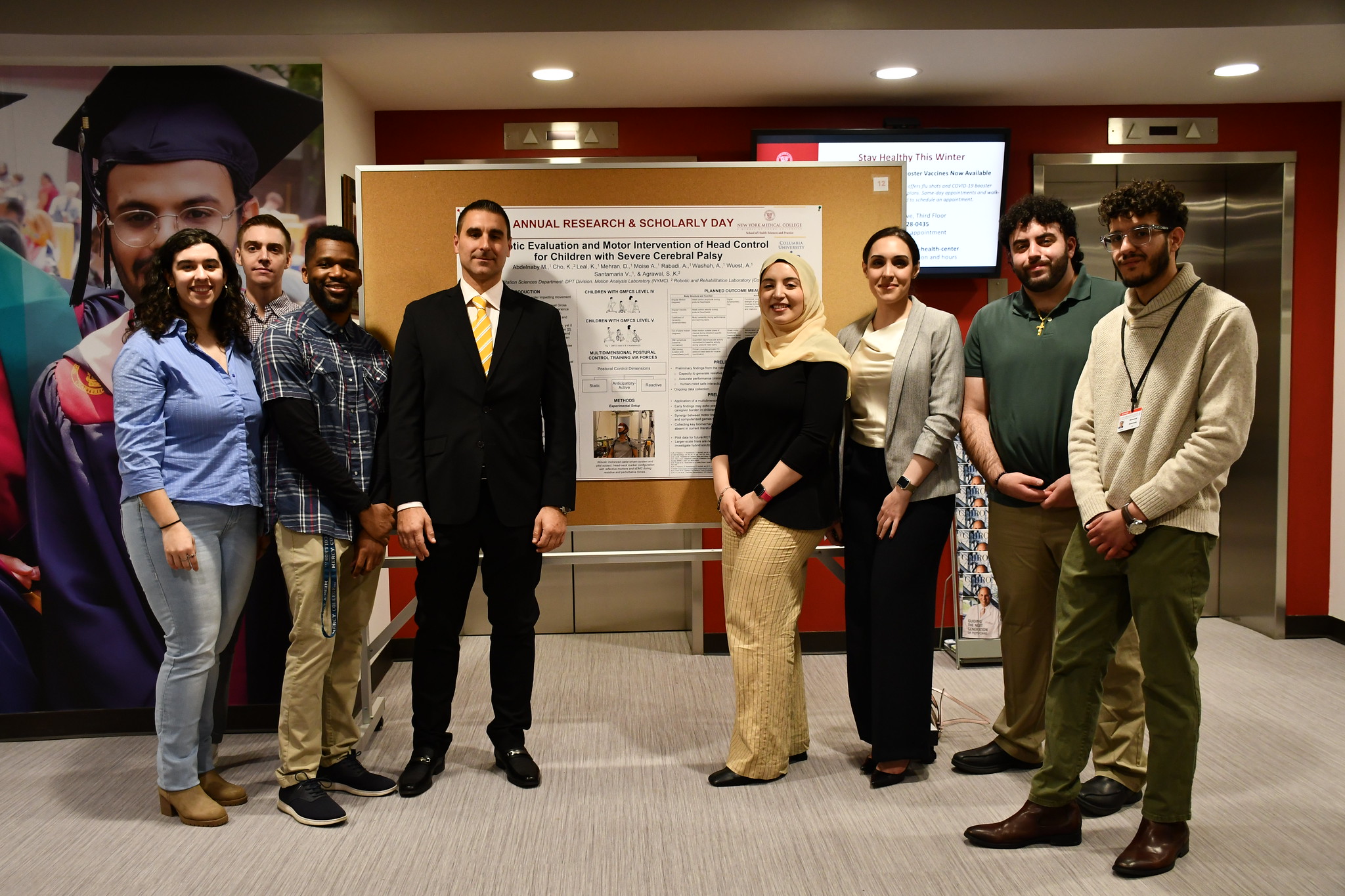 A group of students and SHSP leadership smiling in front of a research poster presentation