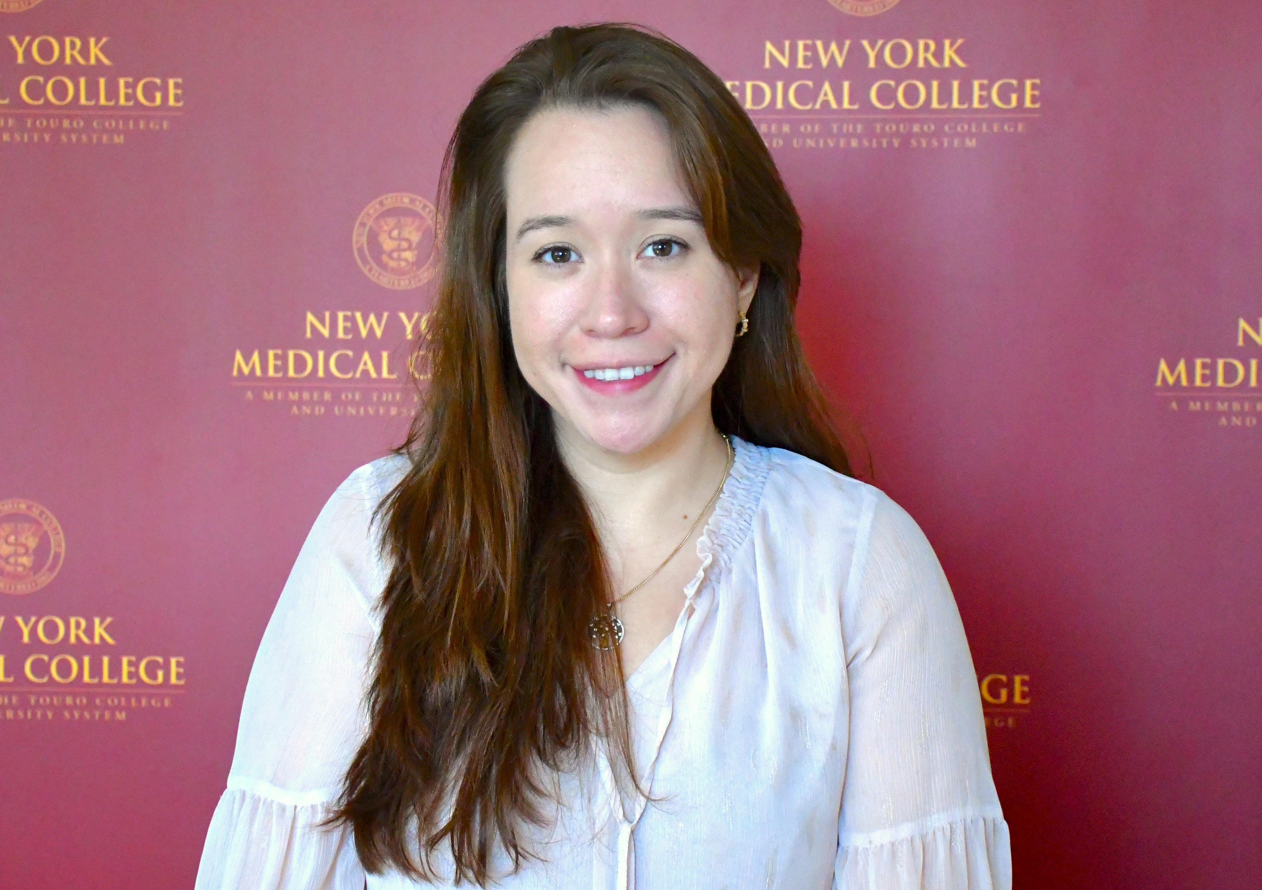 Stephanie Cabrera smiling in front of NYMC step and repeat.