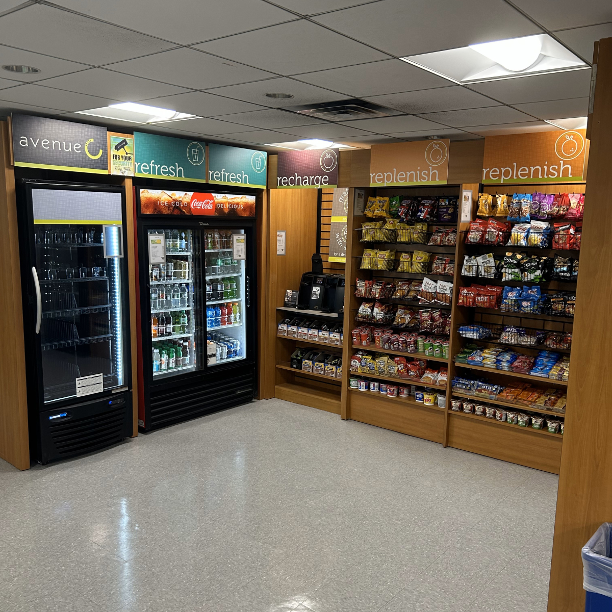 Students and staff in retail dining area with food station and large cooler of drinks.