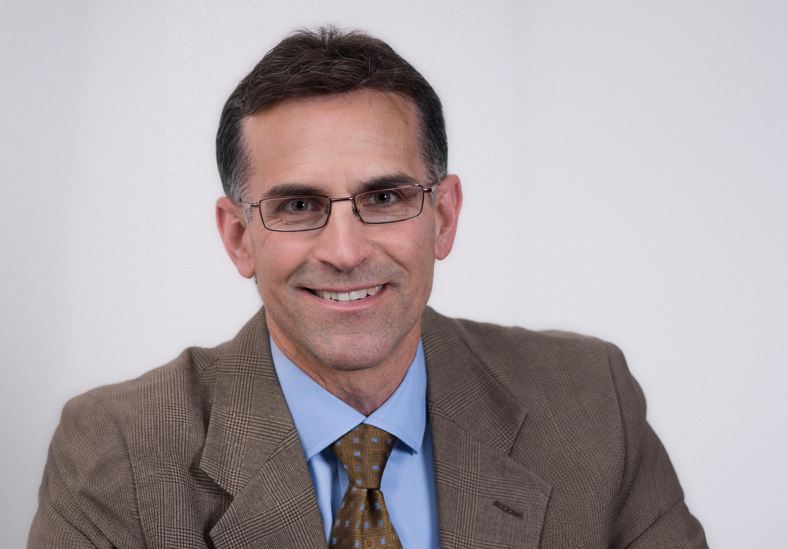 Stephen Ferrando, M.D., photo of man with glasses in brown blazer with blue shirt and tie