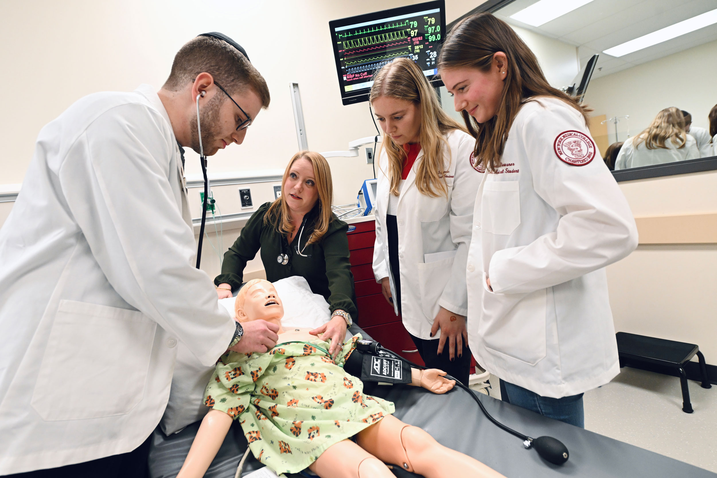 Three students and faculty member working with a dummy on campus