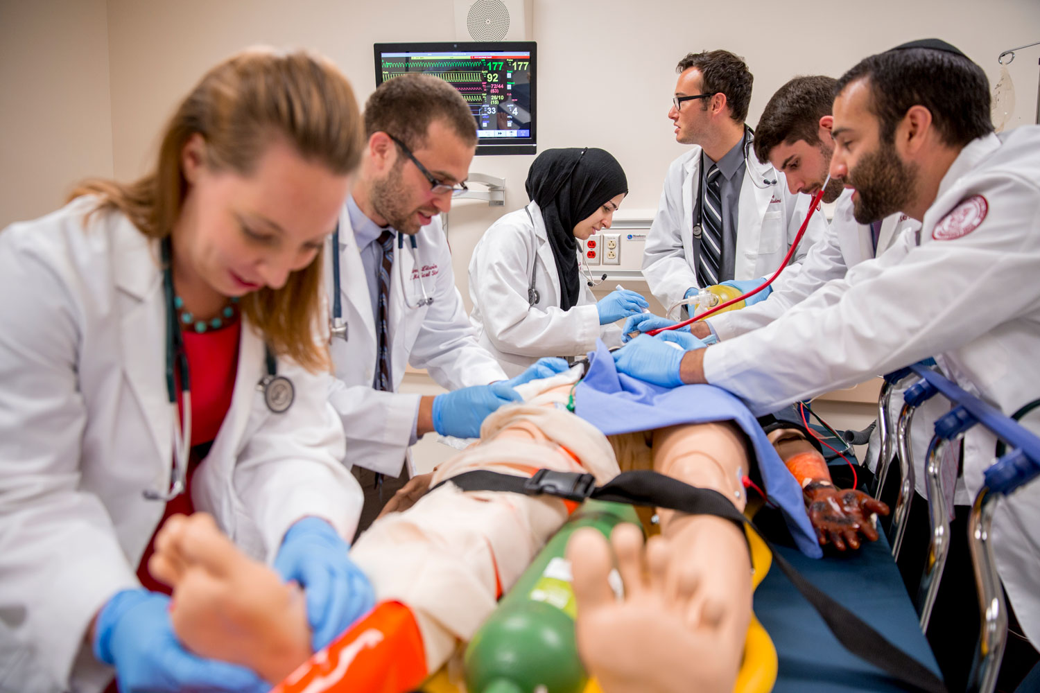 Group of students working on manikin strapped to table